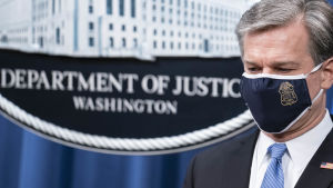FBI-chefen Chris Wray uppmanar extremister att hålla sig hemma under installationsdagen. Liittovaltion poliisin FBI:n johtaja Christopher Wray tiedotustilaisuudessa, jossa kerrotaan syytteistä Kiinan "operaatio Kettujahtiin" liityen. Wrayn kasvoilla on suojamaski.