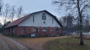 En handelsträdgård verkar i ladugården. En avlång ladugårdsbyggnad av tegel med vitkalkad gavel.