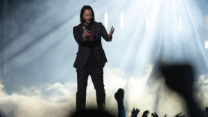 Skådespelaren Keanu Reeves som gör en roll i Cyberpunk 2077 blev till en början nästan en frontfigur för spelet. Nu har Reeves ändå legat lite lägre. En man står med händerna utsträckta rakt framför sig på en scen. Bakom honom ses rök ur en rökmaskin.