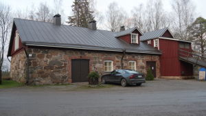 Utställningslokalen Pihatto i Villmanstrand. En lada i sten med en tillbyggnad i rödmålat trä och en ramp. I förgrunden står en bil parkerad.