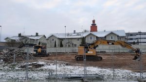 Mellan Korsmansgatan och Bangatan låg tidigare en affärsfastighet med tillhörande parkeringshall. Den har nu rivits och intill kommer att byggas bostäder. Huset i bakgrunden visar hur det såg ut i Hangö centrum förr, innan många av de låga trähusen bombades eller revs. Byggplats