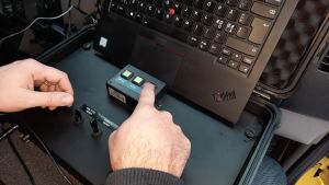 I varje fordon installeras en GPS-enhet. Ett finger trycker på en röd knapp på en enhet som lite liknar en dator.