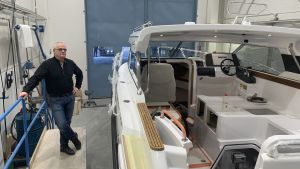 Båtar för över 150.000 euro har åtgång både i Finland och utomlands, vet Olle Granholm på Bella. En man står på en förhöjning intill en stor fritdsbåt som färdigställs i en hall.