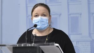 Krista Kiuru tror att vi snart kommer att gå in för nivå 2 i strategin för att bekämpa coronaviruset. Minister Krista Kiuru talar på en presskonferens. Hon har munskydd på sig.