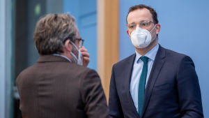 Tysklands hälsominister Jens Spahn hoppas på exportbegränsningar för vaccin som tillverkats inom EU. Två män står och pratar. Mannen till vänster står med ryggen mot kameran. Han är klädd i brun kostym. Mannen till höger står vänd mot kameran. Han har svart kostym, ljus skjorta och en grön slips. Bägge män bär munskydd.