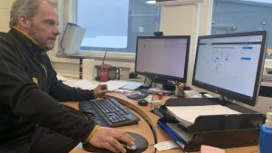 Arbetsledaren Mattias Knuts kollar väderprognosen och konstaterar att snön fortsätter falla flera dagar ännu. En man sitter vid en dator med två skärmar.