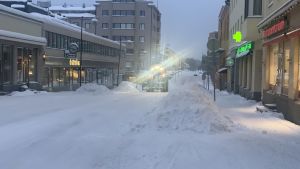 Först plogas centrum, huvudleder och cykelbanor. Sedan bostadsområdena. En fronlastare plogar snö i centrum av en liten stad.