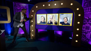 Programledaren Hannes hälsar på SHS som består av Emilia Donner, Emilia Winqvist och Sebastian Ståhlberg. En man sitter i en studio, bredvid sig har han stora skärmar där han ser tävlarna som deltar från sina egna datorer där hemma.