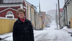Gun Snellman är välinsatt i Skatas historia. Gun Snellman står mitt i Skata medan snöflingor singlar ner.