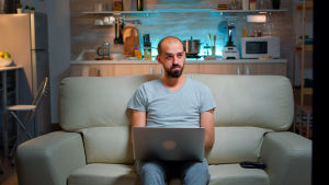 "Jag är en glad och sprallig kille på 48 jordsnurr ..." Man sitter i soffa med dator i famnen och ser fundersam ut