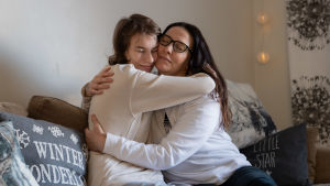 Äiti tukee autismin kirjon omaavaa lasta halaamalla.