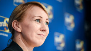 Tingsrätten valde att inte väcka åtal då Hanna Mäntylä misstänktes för bedrägeri efter att ha erhållit tiotusentals euro i rättshjälp år 2010 trots att hon bodde med en välbärgad man. Hanan Mäntylä ler med Sannfinländarnas logo i bakgrunden.