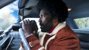 Ron Stallworth (John David Washington) har svårt att fatta vad han blir indragen i. Ron Stallworth (John David Washington) sitter i en bil och spanar med sin kikare.
