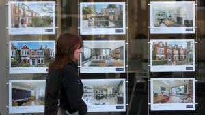 Bostadspriserna i London gick ner kraftigt under år 2009 Kvinna som går framför reklam på hus som är till salu.
