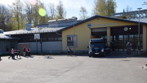 Sjundeå svenska skolas nuvarande byggnad. En skolgård med skolbyggnad och lekande barn.