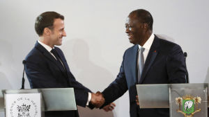 Emmanuel Macron är på besök i Västafrika. Här skakar han hand med Elfenbenskustens president Alassane Ouattara. Två män ser varandra i ögonen och skakar hand.