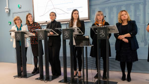 Regeringen har kommit med rekommendationer om att 70-åringar ska hålla sig hemma. Det gäller ändå inte förtroendevalda Regeringens ministrar står bakom talarpodier.