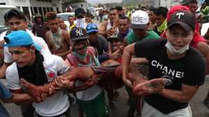 Demonstranter bär på en skadad man. Demonstranter bär en man som skadats i sammandrabbningar vid gränsen mellan Venezuela och Colombia.