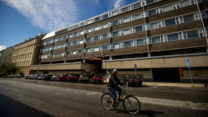 En del av de svenskpråkiga daghemsbarnen flyttade in till yrkesinstitutets lokaler på Klockringaregatan i Åbo. Nu har inneluftsproblem uppdagats i fastigheten En byggnad i tegel och betong, en person cyklar förbi byggnaden.