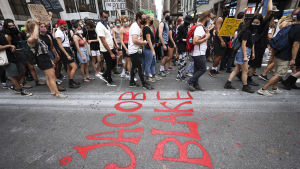 Hundratals demonstranter marscherade i New York på grund av skjutningen Demonstranter tågar längs en gata. Namnet Jacob Blake är målat på gatan.