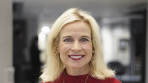 Pia Kauma satt i Esbo stadsfullmäktige medan västmetron byggdes - och var mycket frustrerad. En kvinna står i ett kontorslandskap och ser in i kameran. Hon ser glad ut. Hon är städigt klädd.