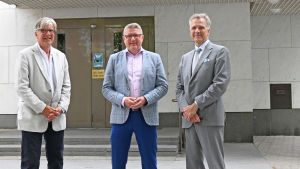 Utanför Ekenäs Sparbank står från vänster Kaj-Erik Nöjd (stiftelsens styrelseordförande), Berndt-Johan Lundström (bankdirektör) och Peter Storsjö (aktiebolagets styrelseordförande) Tre kavajklädda män utanför en bank (Ekenäs Sparbank).