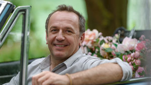 Vem kan motstå en skjuts i en gammal fransk bil med baksätet fullt med rosor? Jacuqes (Arnaud Viard) sitter i en bil med baksätet fullt med blommot och ler.
