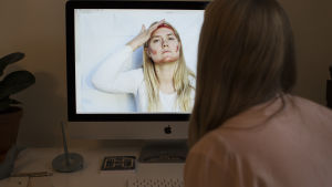 Vanessa Forstén vid datorn. På skärmen ser man hennes videoperformance Warpaint. 