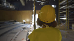 Marit Berndtson glädjer sig åt att renoveringen väldigt långt följer den vision som man haft på teatern. en kvinna med hjälm och reflexväst står med ryggen till kameran och ser ut över en teatersalong under renovering