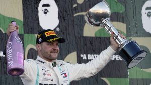 Bottas har vunnit tre tävlingar den här säsongen. Bottas står på prispallen med en champagnefalska i en hand och en pokal i den andra.