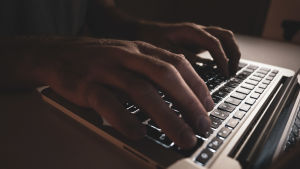 Bästa sättet att skydda sig mot dataintrång är att använda sig av tvåstegsverifiering. Miehen kädet kannettavalla tietokoneella.
