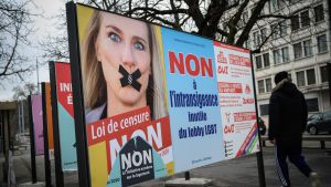 Det nationalkonservativa folkpartiet SVP:s valreklam med partiets Europaparlamentariker Celine Amaudruz. Affischen ber väljarna rösta mot lagen och hävdar att den kommer att leda till censur. En person går förbi en stor valaffisch med en bild på en kvinna med svart tejp över munnen.