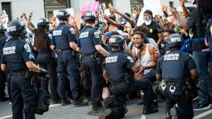 En av demonstranterna ropar ut sin reaktion då polisen knäböjer framför honom. I närheten av Vita huset gick också en av poliserna ner på knä inför demonstranterna. Protesten i knäböjande position introducerades redan 1965 av Martin Luther King.