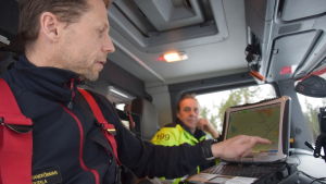 Brandförman Mikko Routala söker rätt plats på kartan. Brandförman Mikko Routala visar på en karta i brandbilen.