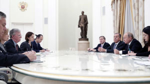 John Bolton i mitten till vänster om bordet, Vladimir Putin och Sergej Lavrov till höger. John Bolton, Vladimir Putin, Sergej Lavrov och medarbetare sitter vid ett runt, vitt bord.