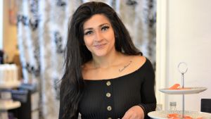 Angelina Hintsanen driver frisörsalongen Salon Davini på Kungsgatan Kvinna med långt mörkt hår ler mot kameran.