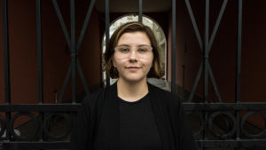 Hanna Lagerström rappar på Närpesdialekt. Hanna Lagerström står svartklädd framför ett stängsel och tittar in i kameran.