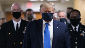 Det är inte många gånger president Trump använt munskydd i offentligheten, men nu uppmanar han alla amerikaner att göra det som en "patriotisk handling". Donald Trump i ansiktsskydd. Bakom honom syns fler personer bära mask.