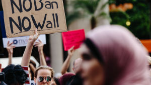 Det ursprungliga inreseförbudet utlöste stora demonstrationer. Flera delstater stämde staten för att få det kullkastat. Demonstration mot inreseförbudet. En kvinna håller en skylt och en annan kvinna klädd i hijab syns i förgrunden.