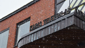 En bild på ett tegelhus med skylten "Karis telefon" skrivet med svarta bokstäver.