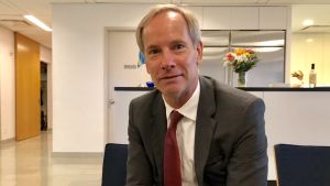 Olof Skoog, Sveriges FN-ambassadör. Porträtt av Sveriges FN-ambassadör Olof Skoog, brundbränd, leende, med röd slips på sned.