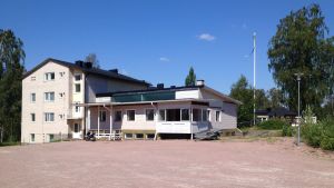 Solgården fanns tidigare i Katarinahemmet i Karis. Vit tegel- och träbyggnad på sandplan med gräs och träd omkring.