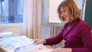 Mikaela Björklund En kvinna med glasögon bläddrar igenom en bunt med teckningar.