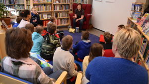 En grupp skolelever sitter i en halvcirkel runt författaren Karin Erlandsson i biblioteket i Dalsbruk.