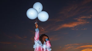 Artisti Nao promokuvassa kolmen ilmapallon kanssa