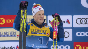 Johannes Hösflot Kläbo står med skidorna höger hand och stavarna i vänster.