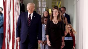 Många av dem som deltog i en tillställning i Vita huset för en vecka sedan då president Trump utsåg Amy Coney Barrett till sin kandidat för domarposten vid Högsta domstolen har nu smittats av coronaviruset. USA:s president Donald Trump går bredvid Amy Coney Barrett. Båda ler. Bakom dem står Coney Barretts barn.
