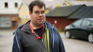 Fredrik Lindgren ser ljus och mörker och kan urskilja solen och skuggor. En man med kort mörkt hår och glasögon. Han står ute på en innergård med parkerade bilar och hus i bakgrunden.