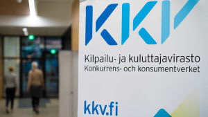 Konkurrens- och konsumentverket framför oro över att munskyddsanvändningen blir ojämlik. En närbild på en skylt med texten KKV, Konkurrens- och konsumentverket. I bakgrunden syns en människa som går längs KKV:s korridorer.