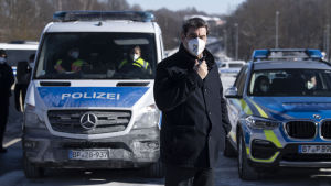 Bayerns regeringschef Markus Söder på besök vid en gränsövergång till Tjeckien. Två polisbilar vid landsgräns mellan Tyskland och Tjeckien. Framför dem står en man i svart rock.